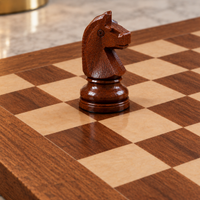 Cavalier d’échecs en bois teinté brun foncé, sculpté avec des détails texturés, posé sur un échiquier en bois composé de cases claires et foncées.