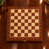 Échiquier pliant en bois de 34 × 34 cm, sans pièces, posé sur une table en bois brillant, avec cases claires et foncées, coordonnées et fermoir métallique doré.
