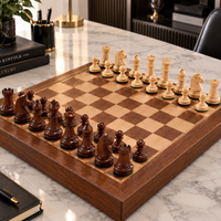 Jeu d’échecs en bois composé de pièces claires et brun foncé, disposées sur un échiquier en bois posé sur une élégante table en marbre blanc.