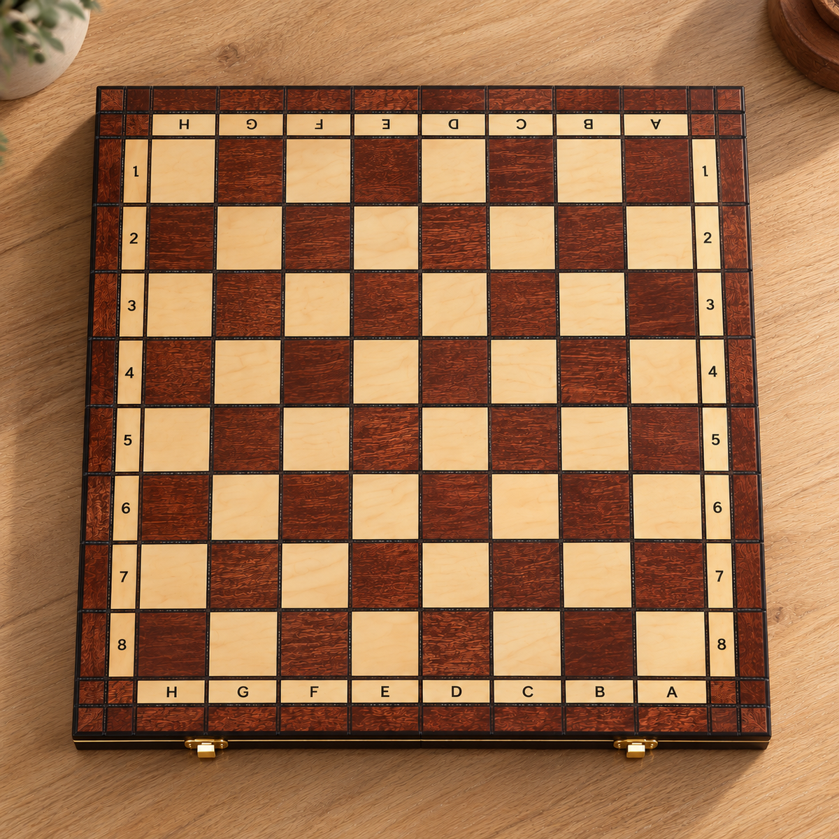 Échiquier pliable en bois de 44 x 44 cm posé sur une table en bois clair, avec cases claires et brun foncé veinées et coordonnées A-H et 1-8 visibles sur la bordure.